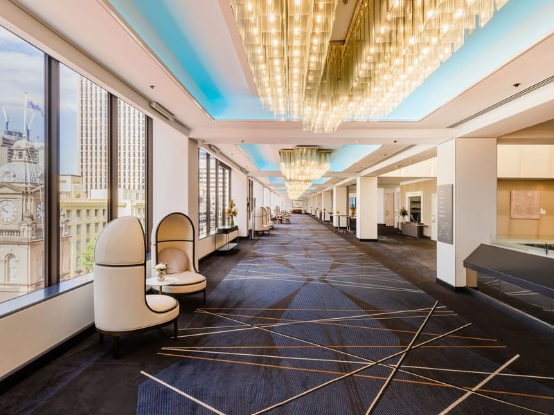 Elegant event lobby with floor-to-ceiling windows, golden chandeliers, and modern seating at Sofitel Brisbane Central