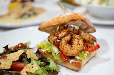 Delicious shrimp sandwich on a ciabatta bun, served with a side salad at The Boulevard Inn & Bistro