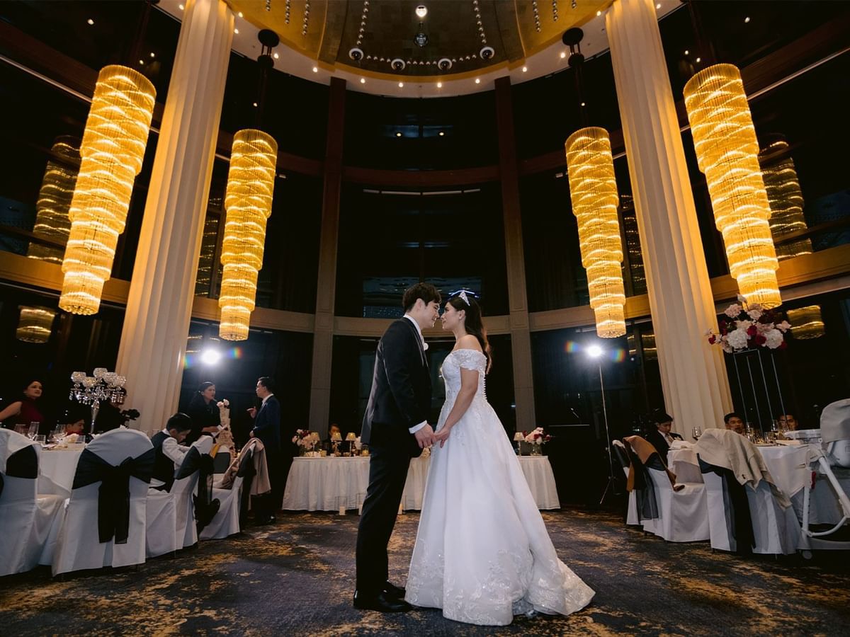 Felicia and Jonathan holding hands in a grand wedding hall at Crown Towers Perth