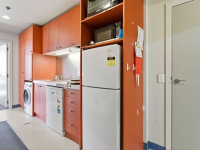 Orange cabinets, white appliances, and a washer dryer combo in a room at UniLodge Stafford House.