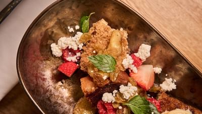 An artistic fine dining dessert beautifully garnished with fresh strawberries and edible flowers.