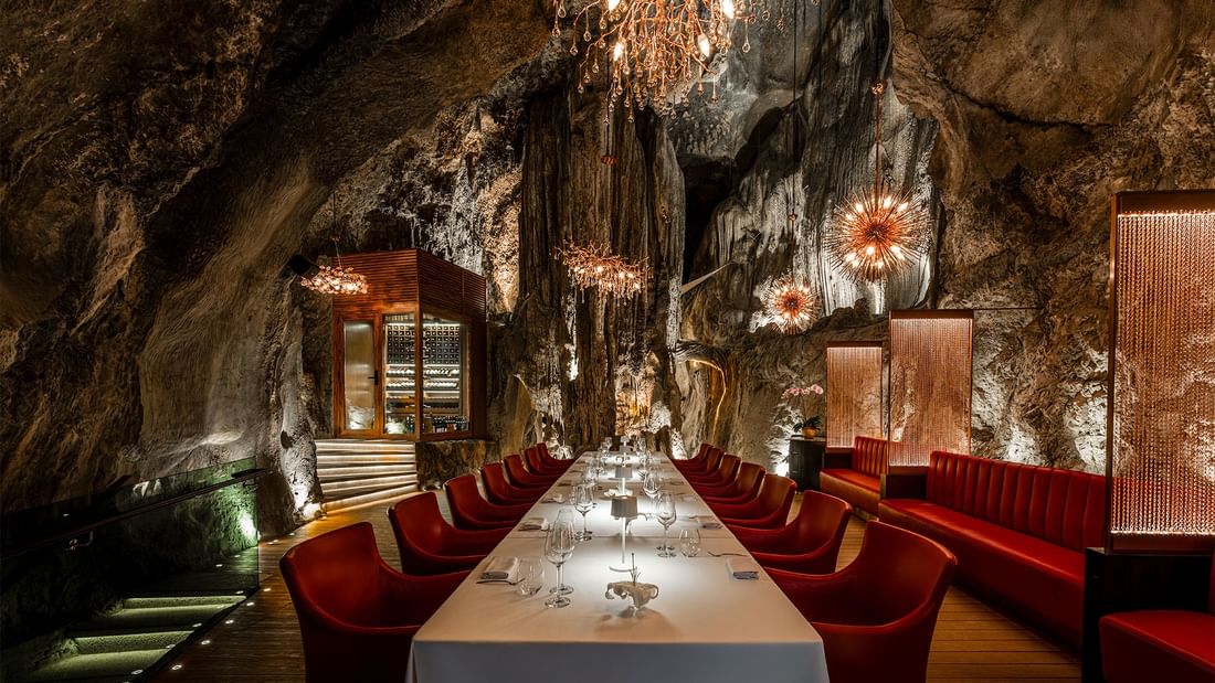 Jeff's Cellar private dining space with long table, red chairs in a cave at The Banjaran Hotsprings Retreat in Ipoh.