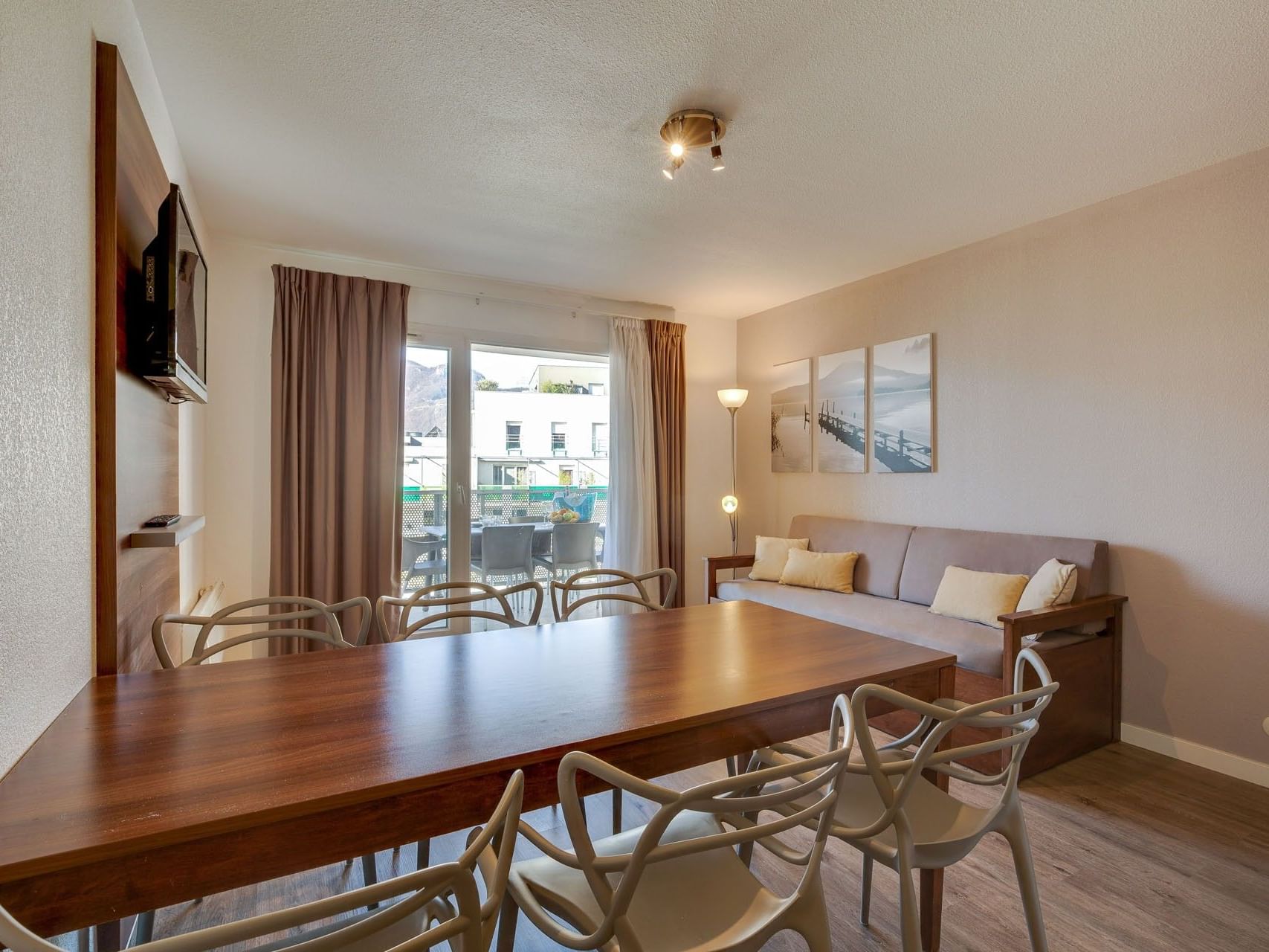 Living area with a wall-mounted TV and dining table in the Two-Bedroom Apartment at ResidHotel Aix-les-Bains Azurea