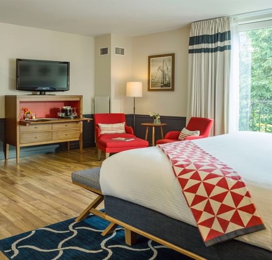 Two ottomans & sitting area by the bed in a room with wooden floors at Portland Harbor Hotel