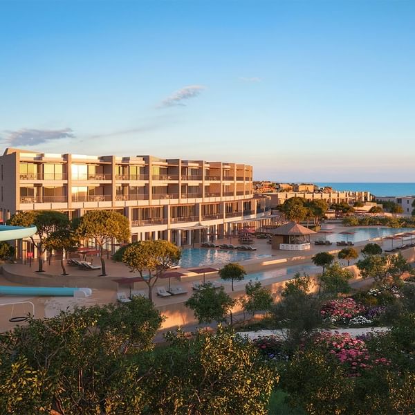 Hotelski kompleks s bazenima, barom, ležaljkama i oceanom u daljini.