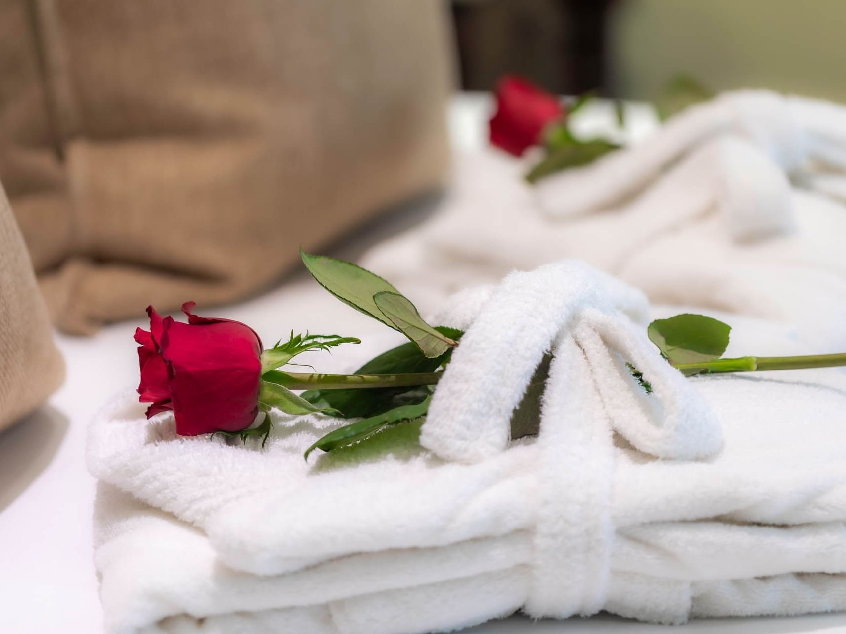 Bath rob with a red rose on a bed at Cardoso Hotel