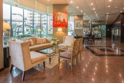 Lobby with elegant seating, art on the walls, and large windows at Hotel Los Delfines & Casino