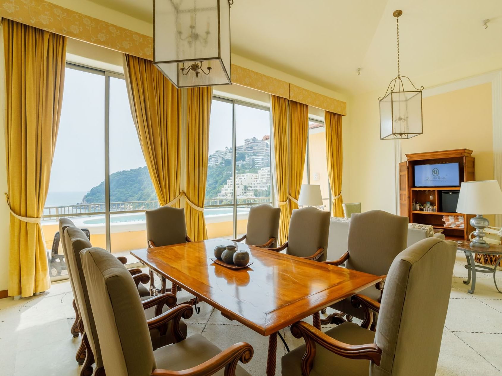 King Presidential Suite dining area featuring a large wooden table and stunning balcony views at Quinta Real Acapulco