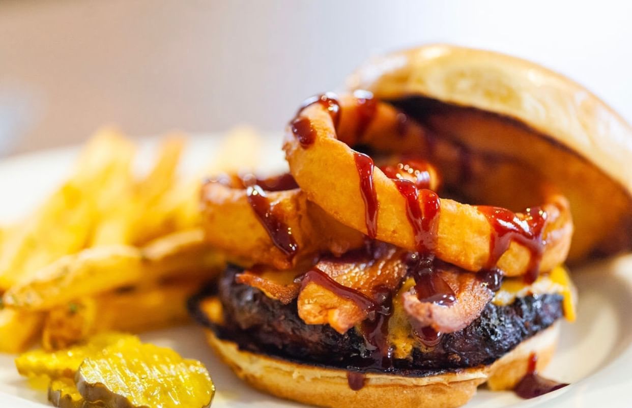 A burger with fries and pickles on a plate