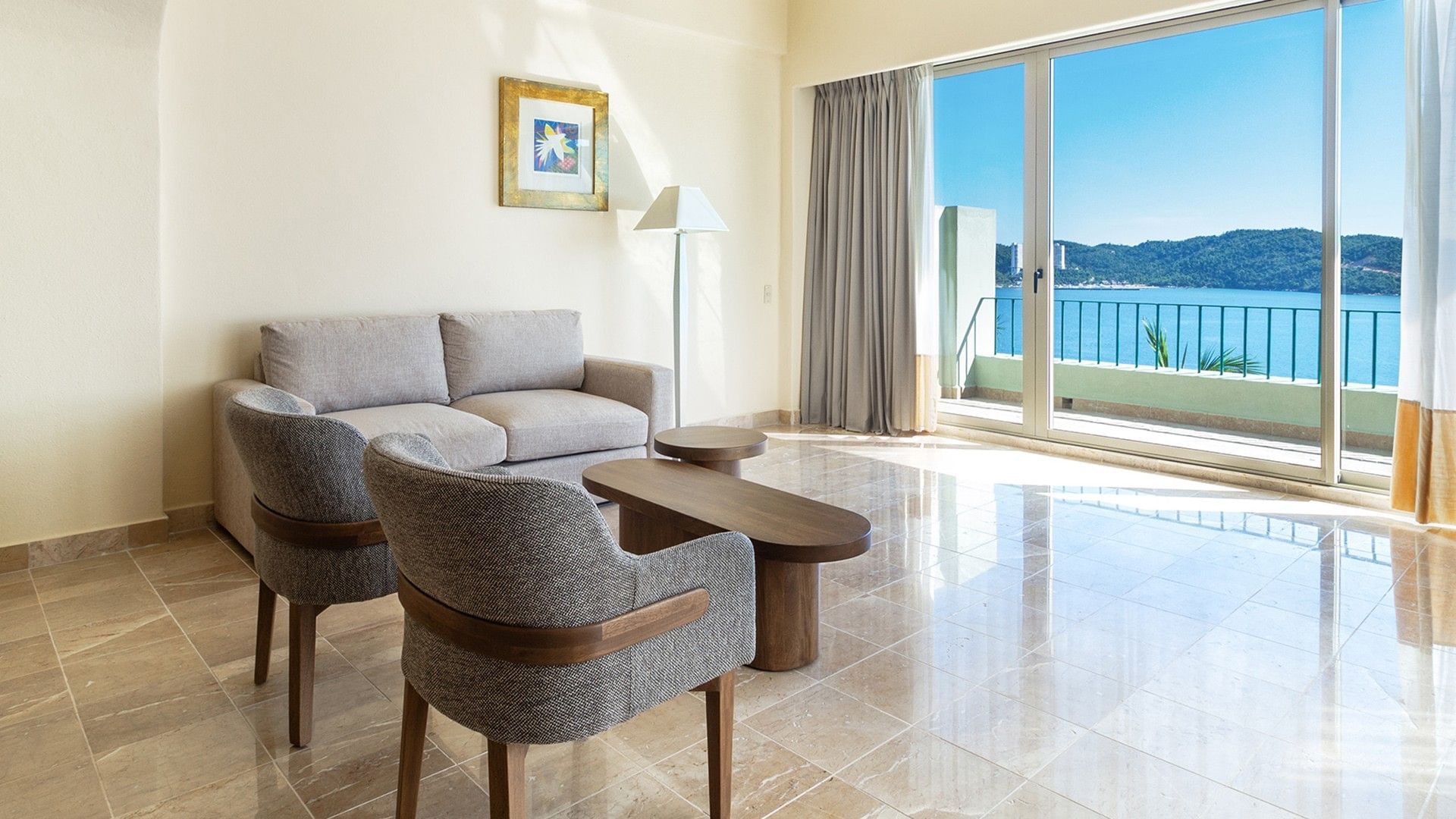 TV lounge area by the bed in the King Master Suite with a balcony seating area at Camino Real Acapulco Diamante