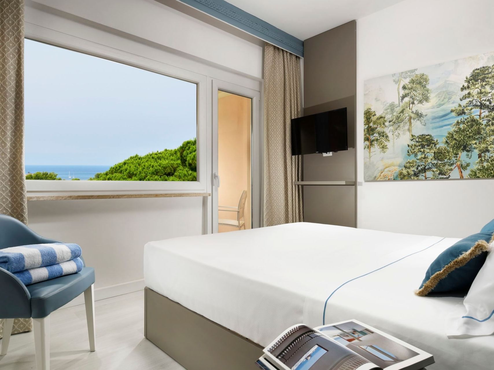 Bed & TV with a lake wallpaper in Deluxe Double Room Sea View at Golf Hotel Punta Ala