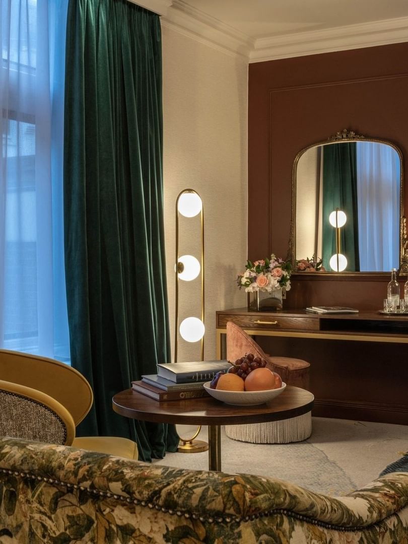 Elegantly furnished Deluxe Room with floral couch, books, & fruit at The Capital Hotel, Apartments & Townhouse, London