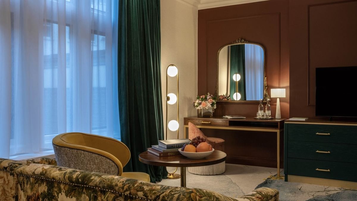 Elegantly furnished Deluxe Room with floral couch, books, & fruit at The Capital Hotel, Apartments & Townhouse, London