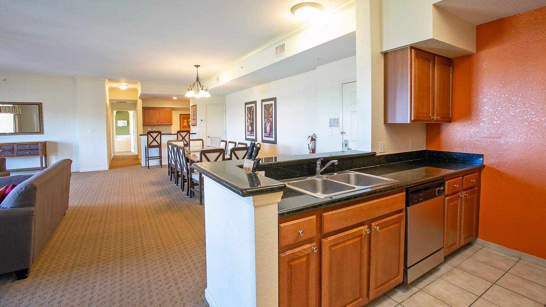 A wide view of a kitchen and living area with a dining table, sofa, and kitchen island.