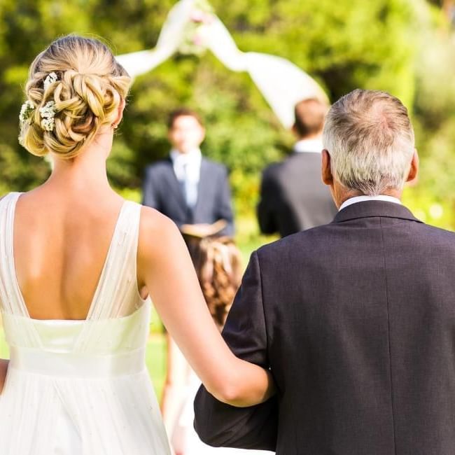 Bride accompanied by dad walking down the aisle  