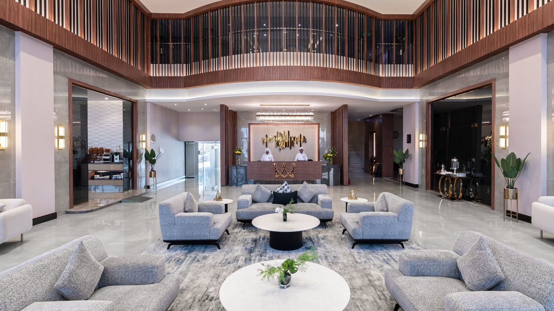 Warwick Al Jubail Hotel lobby featuring plush gray sofas, round marble tables, and a reception area with staff