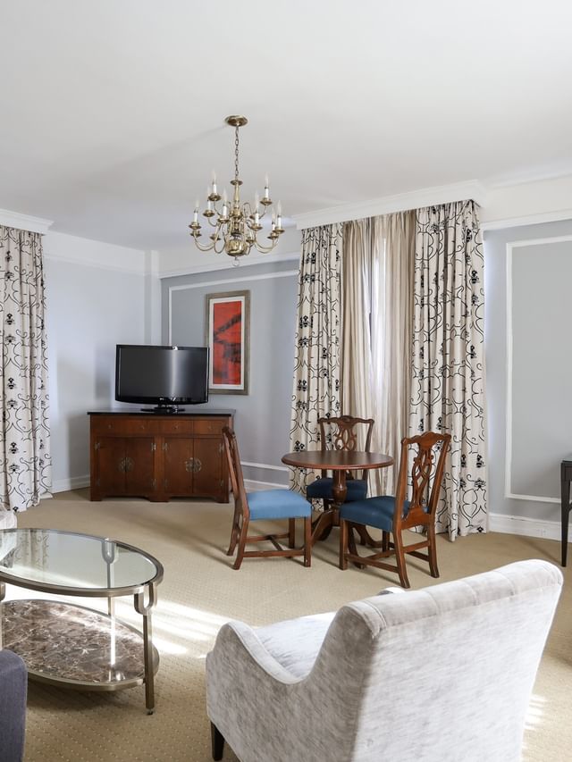 Bright sitting area in Parlor Suite with velvet armchairs, a glass table, and a chandelier at Arlington Resort Hotel & Spa