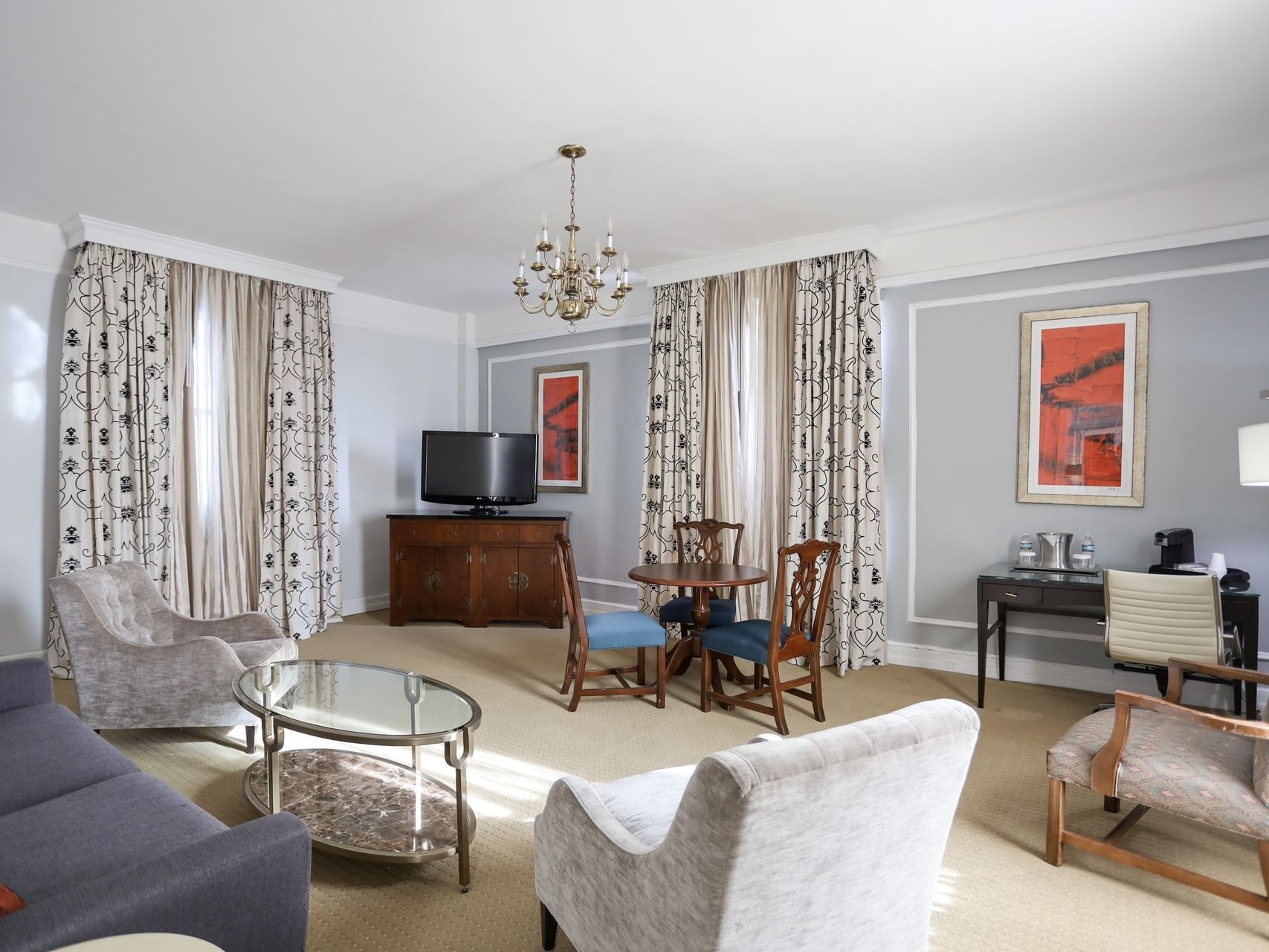 Bright sitting area in Parlor Suite with velvet armchairs, a glass table, and a chandelier at Arlington Resort Hotel & Spa