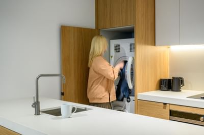 A lady put clothes into a washing machine at Nesuto Docklands