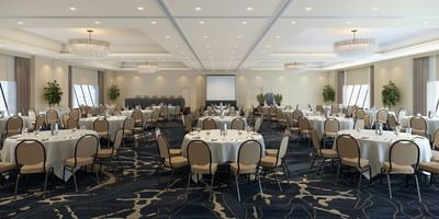 The Baronet Ballroom conference room at the Hotel Halifax in Nova Scotia with round tables, chairs, chandeliers, and stage.