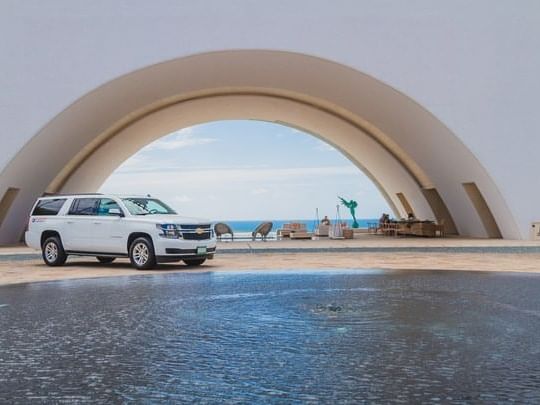 Un automóvil estacionado cerca de un voladizo curvo junto al mar en Los Cabos