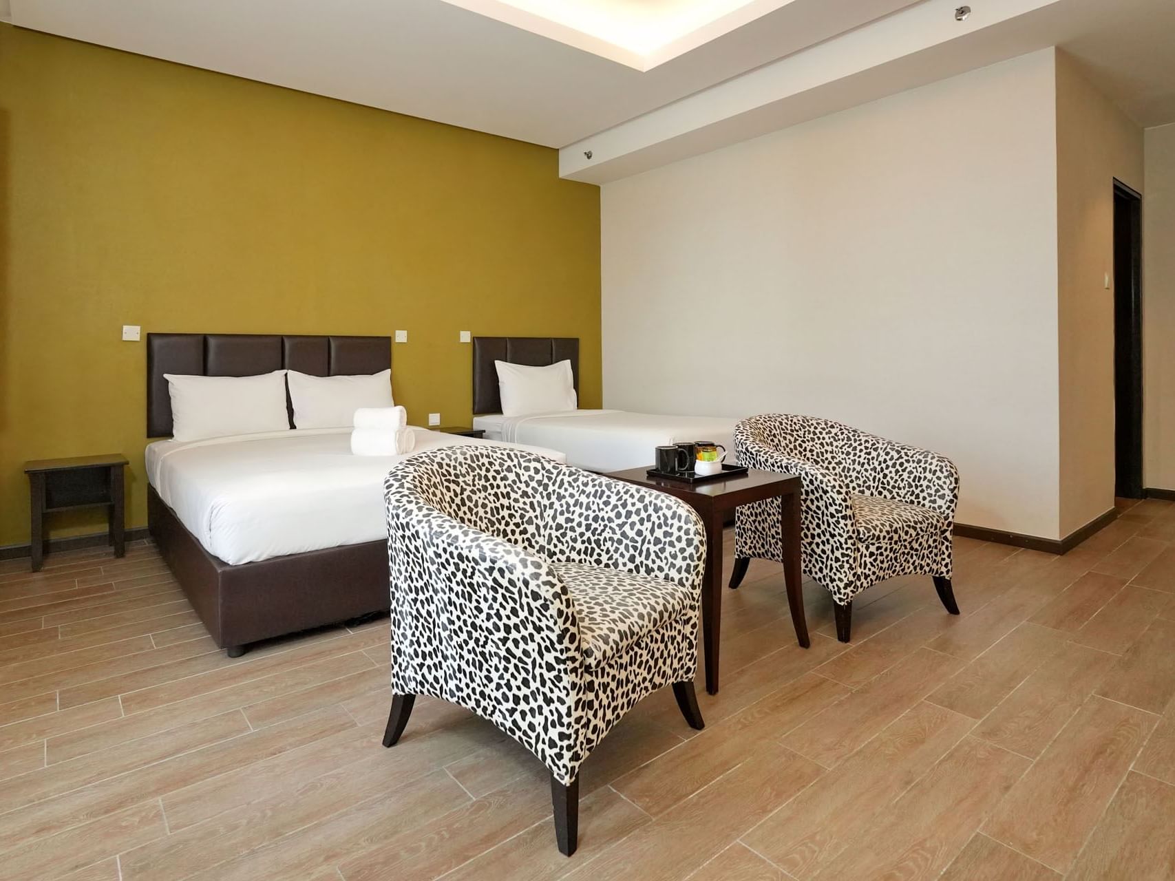 Seating area by the beds in Deluxe Triple with wooden floors at Cititel Express Ipoh