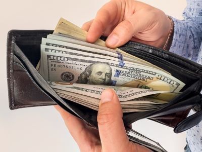 Man shows his wallet full of US dollars (shutterstock_2459760789.jpg)