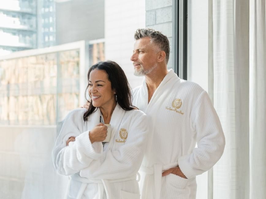 Couple in robes by window, enjoying the view, for Boxing Week Sale.