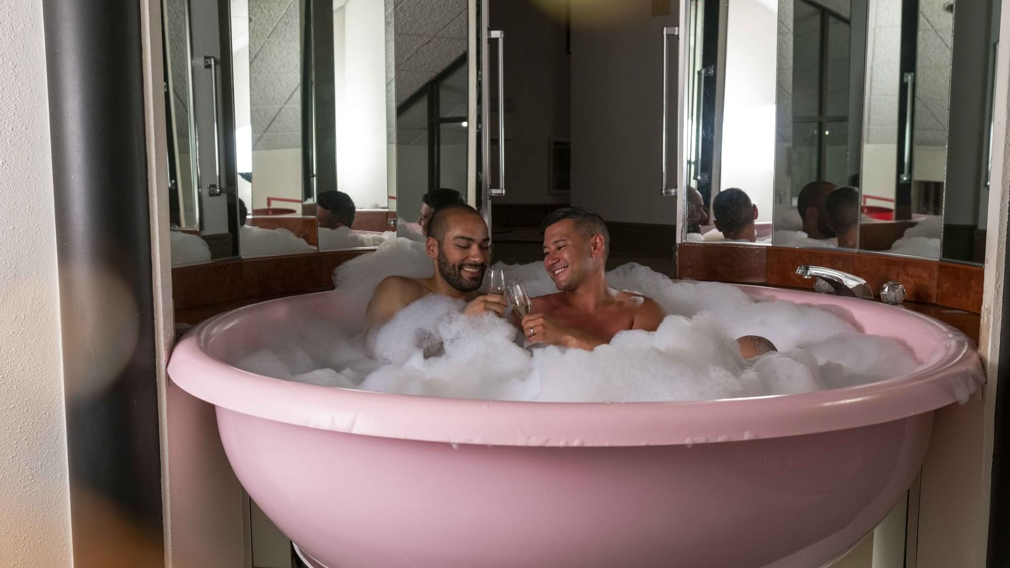 Couple playing with bubbles in the Champagne Tower Suite bathtub at Cove Pocono Resorts