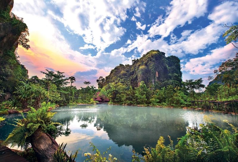 Calm lake resting among lush green mountains beneath a clear blue sky near Sunway Resort