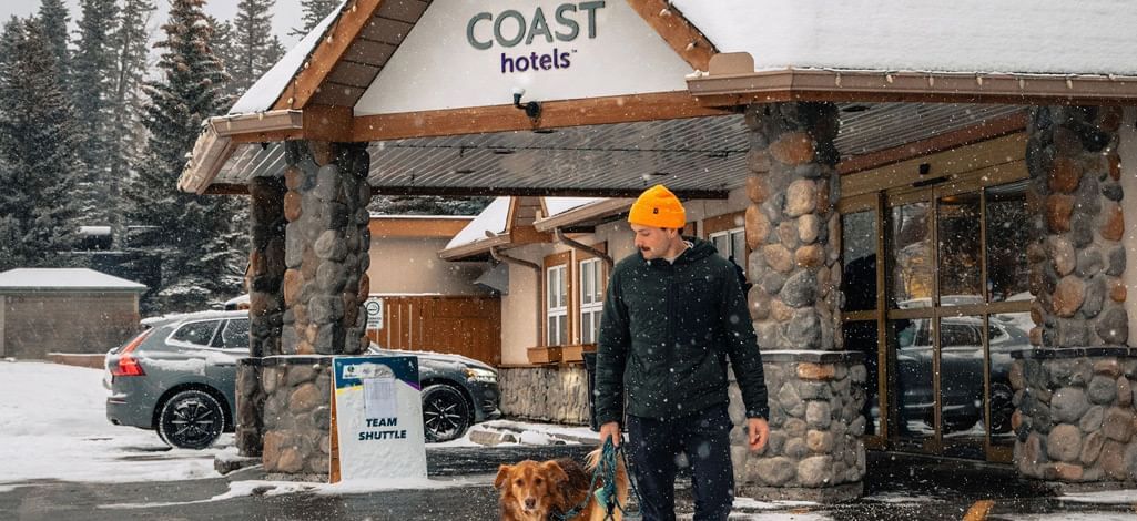 A man and his dog leave the Coast Canmore Hotel & Conference Centre for a day of pet-friendly activities in Canmore.