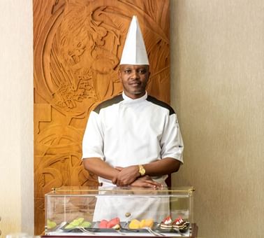 Chef posing with food showcase in front at Kampala Serena Hotel