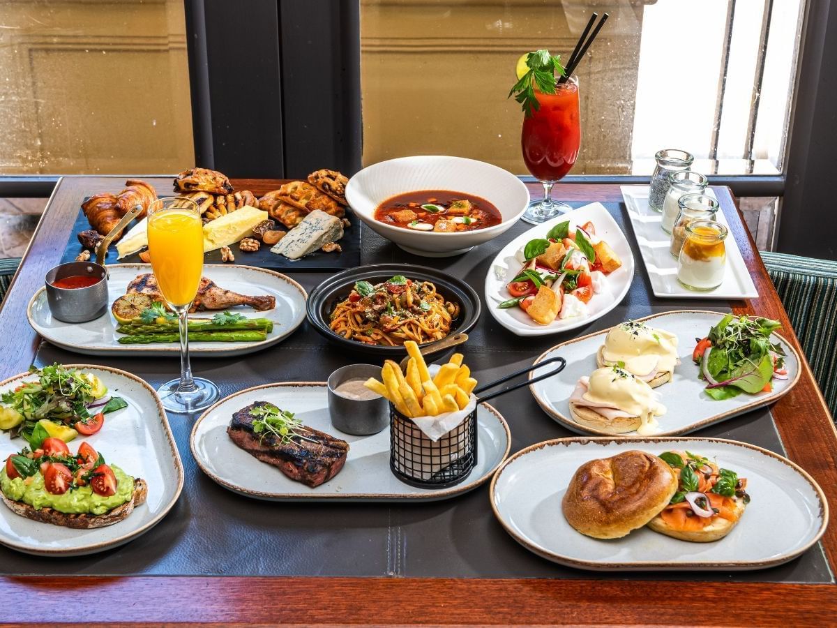 Diverse brunch spread featuring salads, pasta, meats, pastries, and drinks, on a table at Duxton Hotel Perth