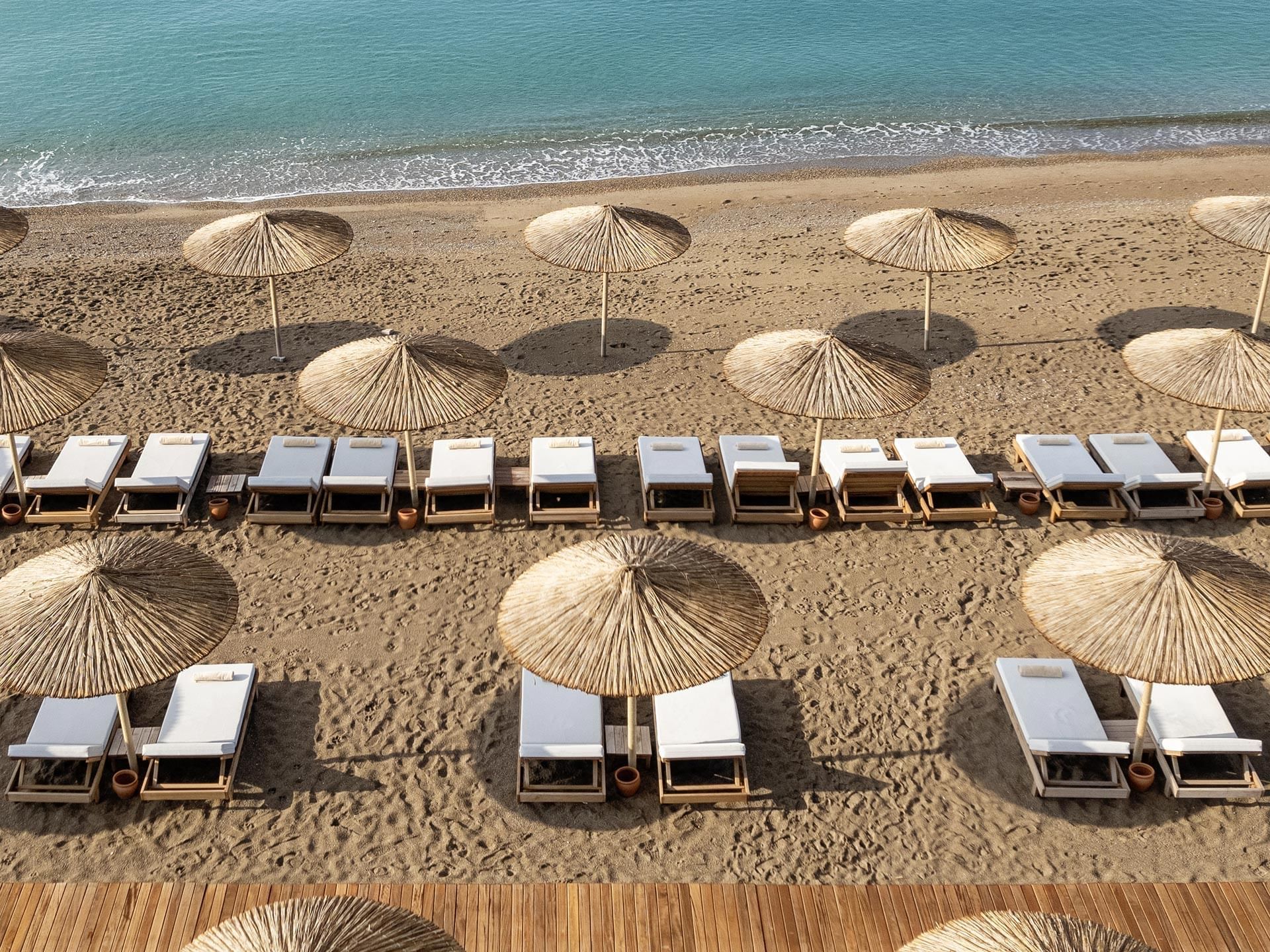Sun loungers lined up under beach huts and overlooking Lara Beach near Titanic Deluxe Lara