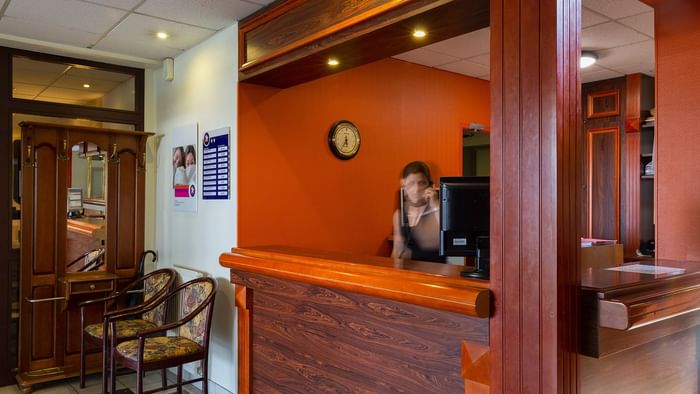 A receptionist at the reception desk in Le Logis d'Elbee