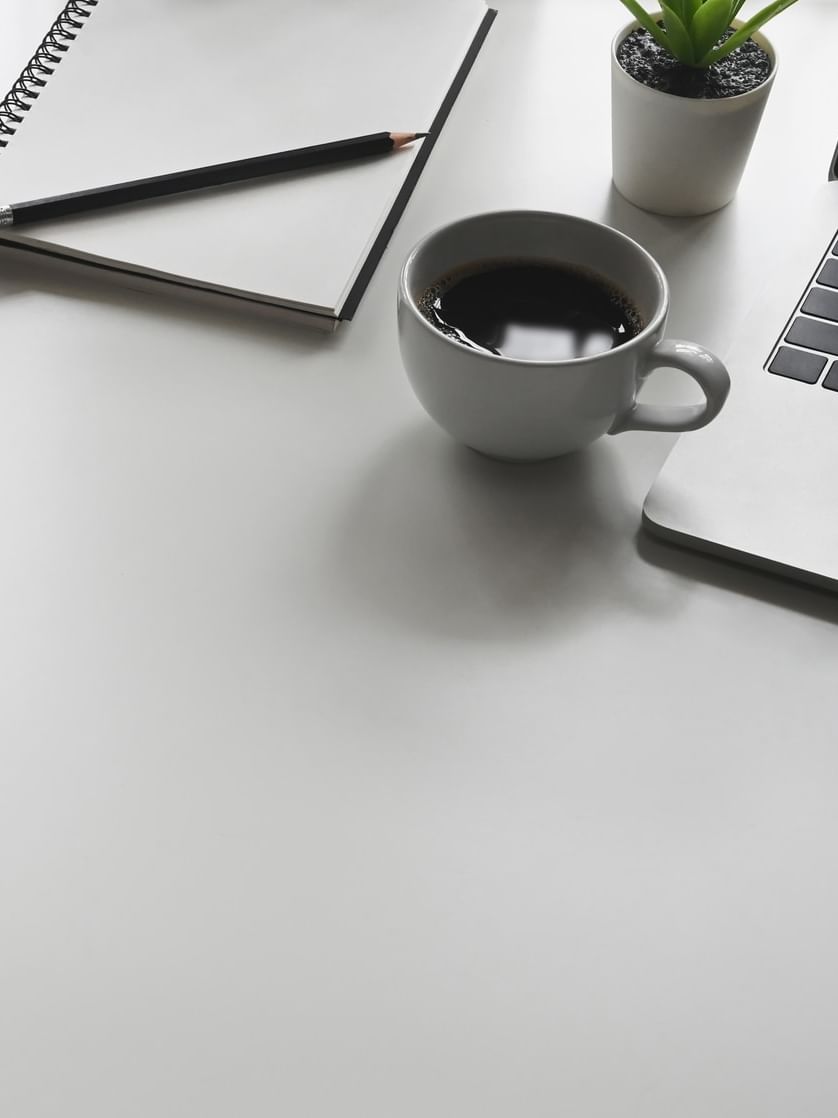 Office desk with laptop, notebook, and coffee at Warwick Al Khobar in Al Khobar.