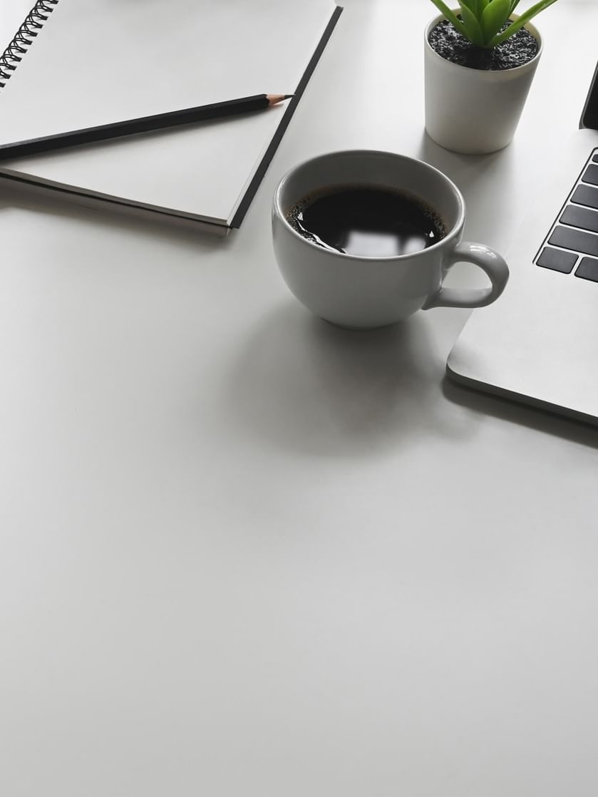 Desk with coffee, notebook, and laptop at Jeddah Hotel & Spa in جدة.