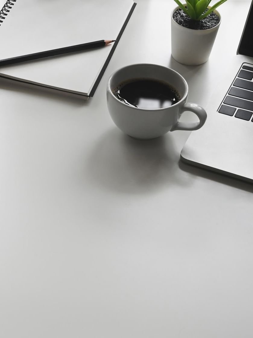 Desk with coffee, notebook, and laptop at Jeddah Hotel & Spa in جدة.