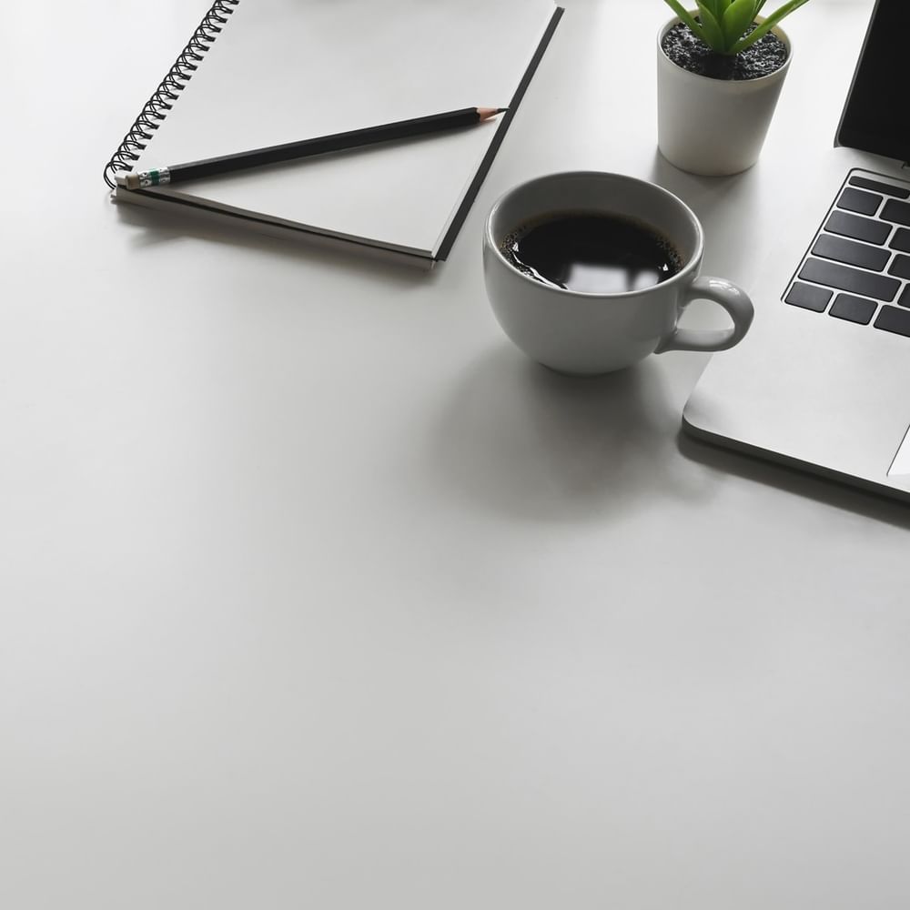 Desk with coffee, notebook, and laptop at Jeddah Hotel & Spa in جدة.