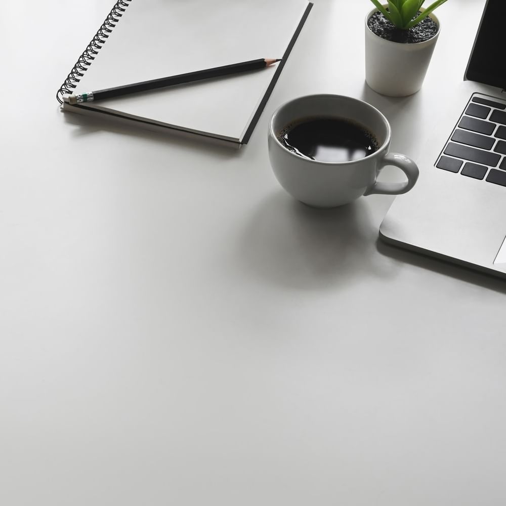 Desk with coffee, notebook, and laptop at Jeddah Hotel & Spa in جدة.