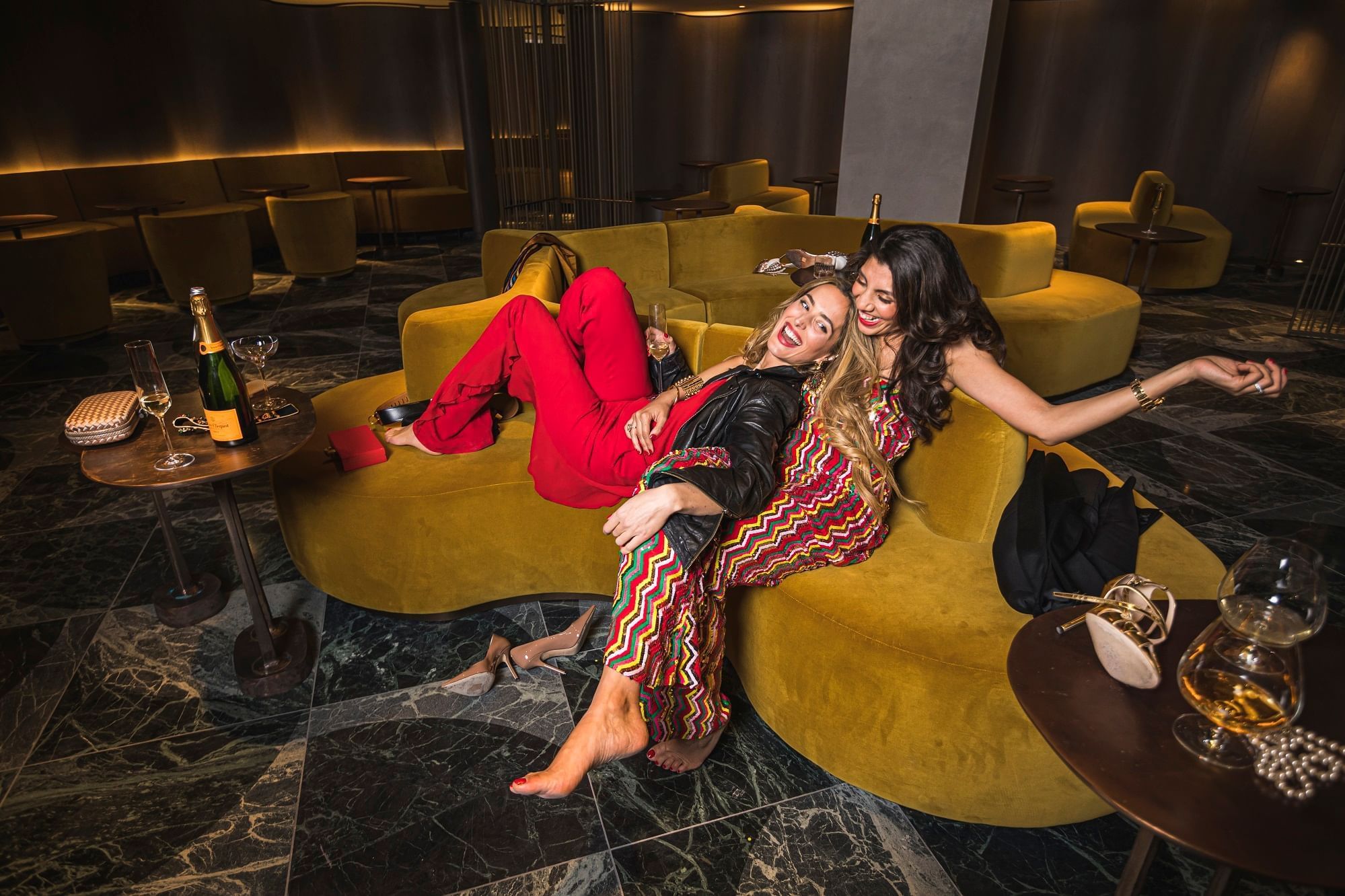 Two girls on the sofa and enjoying champagne at The Londoner Hotel