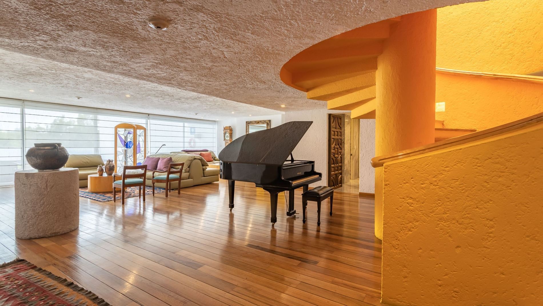 Grand black piano in King Presidential Suite featuring a unique yellow spiral stair at Camino Real Polanco Mexico
