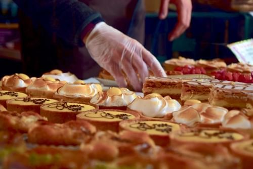 A gloved hand arranges beautiful pastries on a tray.