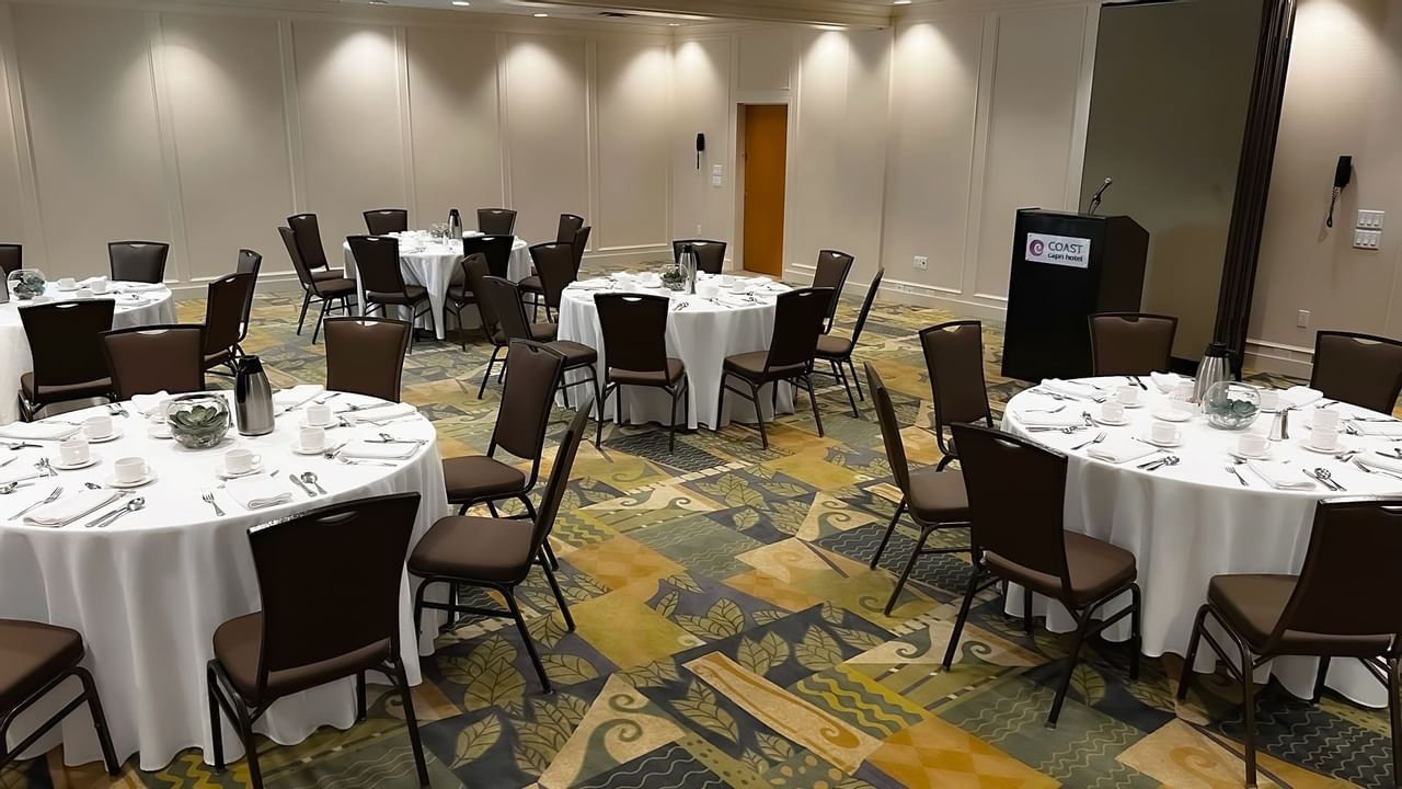 Ballroom with round tables and chairs facing podium