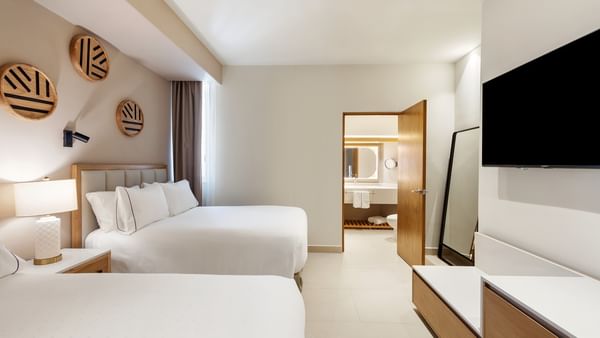 Suite De 2 Habitaciones Con Vista Frontal Al Mar with two beds, a TV, and an open bathroom door at Sunvivia Mazatlán