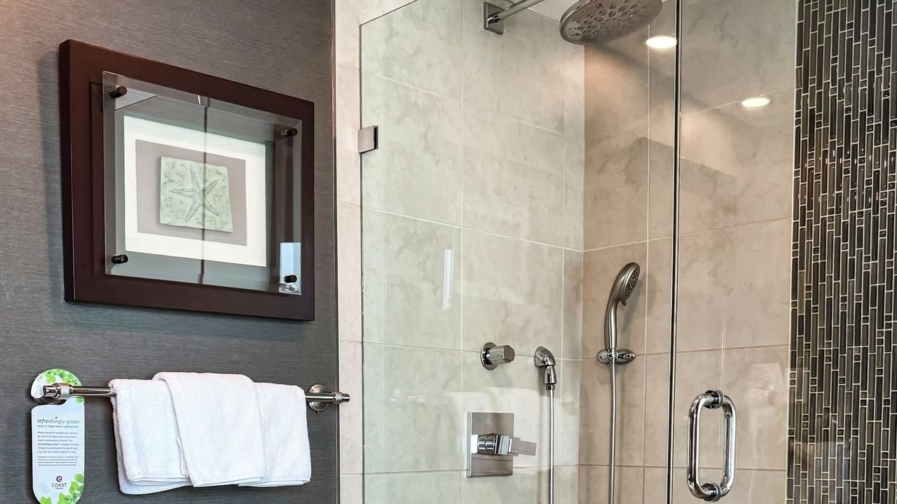 Coast Carrie Cates Penthouse Suite bathroom with glass shower, framed wall art at Coast Lonsdale Quay Hotel