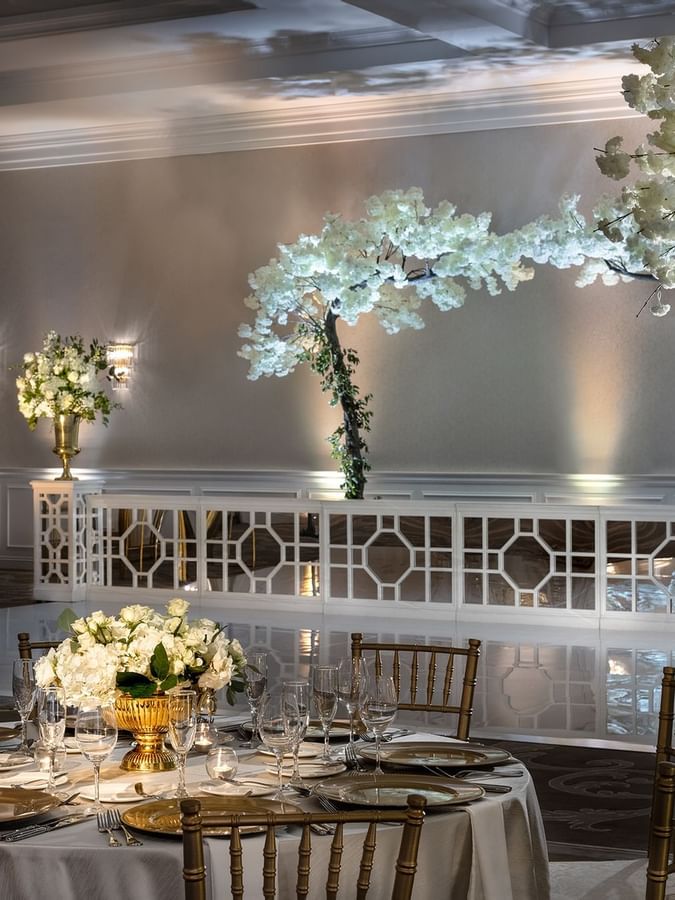 Round table by gold chairs under crystal chandeliers in Turtle Creek Ballroom C at Warwick Melrose Dallas
