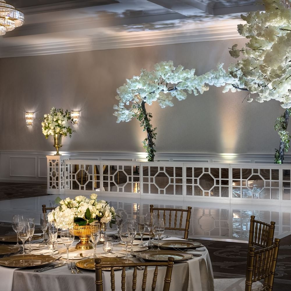 Round table by gold chairs under crystal chandeliers in Turtle Creek Ballroom C at Warwick Melrose Dallas