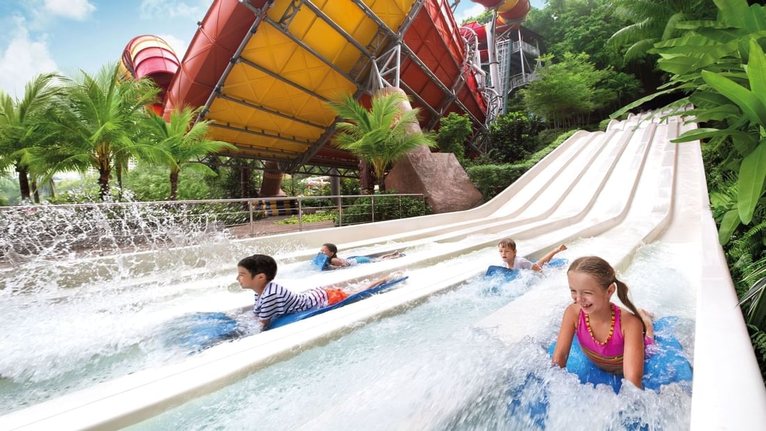 Four children riding boogie boards on a multi-lane waterslide at Sunway Velocity Hotel