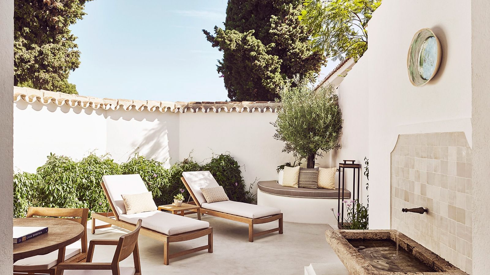 Sun-drenched, Chiquita private outdoor patio with two lounge chairs, a curved bench at Marbella Club